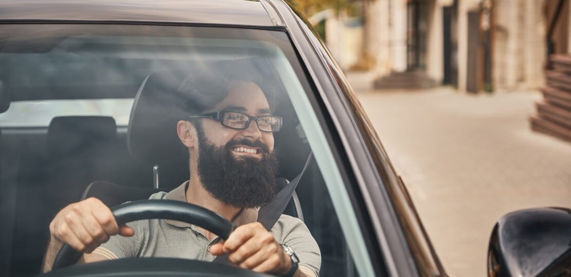 A modern bearded man driving a car